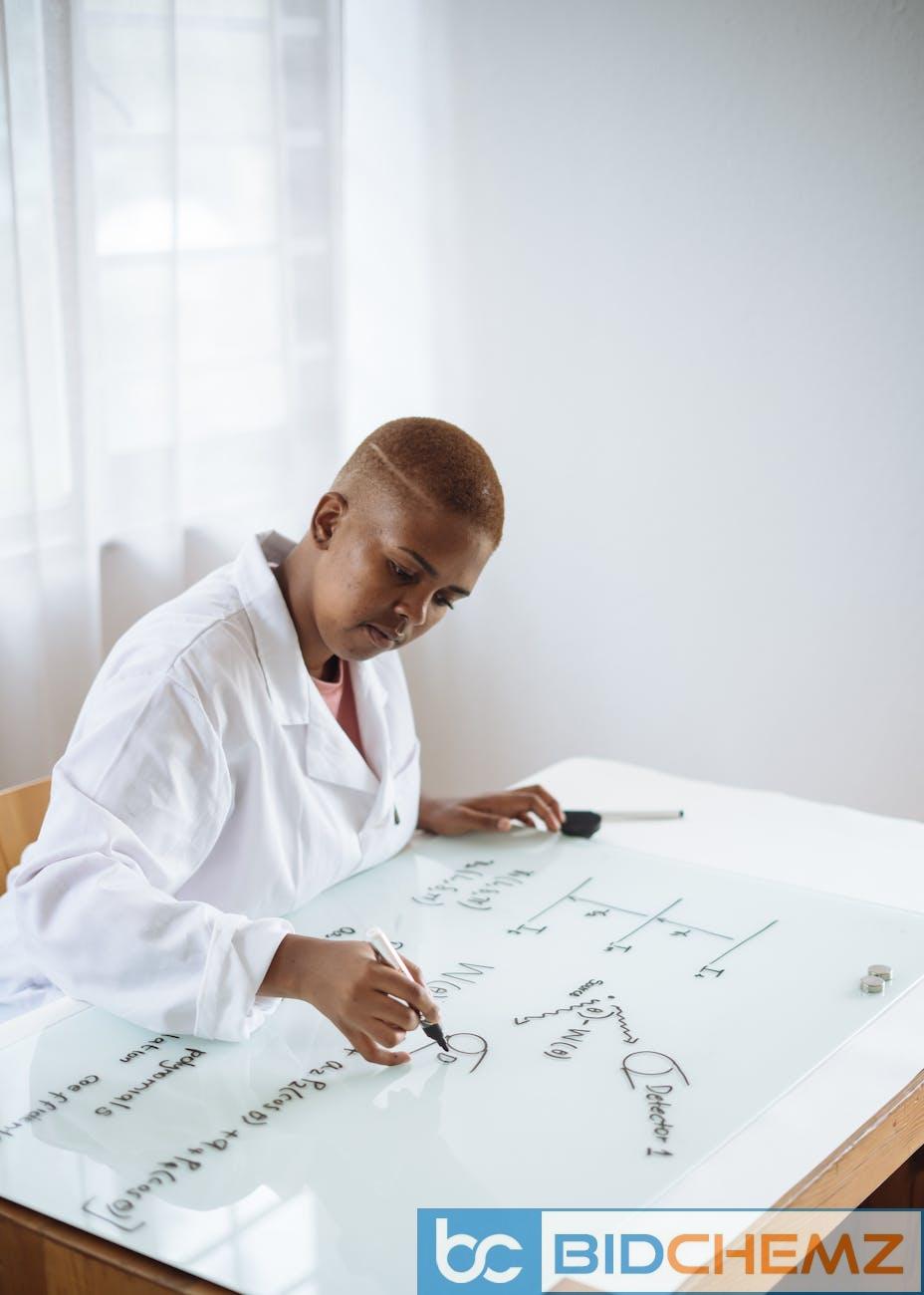 focused african american teenage chemist working on formula in scientific center